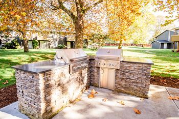 A stone outdoor kitchen with a grill and sink.